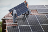 Two installers fitting solar panels onto a residential rooftop