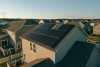 Aerial view of a suburban home with a full solar panel system installed across the rooftop.