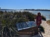 Artist Lily Wilson stands next to the sign featuring her commissioned work 'Wargul and the Swan River' 