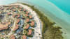 Resort residences framed by greenery and water, featuring a central pool and seamless indoor-outdoor living.