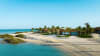 Villas set among palm trees and desert sands, reflecting the beachfront setting at Shura Island.