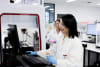 AGRF Melbourne Laboratory, showing automated liquid handling instrument used for genomic sequencing, with two staff members.