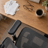 A Sihoo Doro S300 chair's armrest and seat edge sits in the lower third of the frame. 