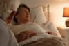 A man comforts his wife who is lying in bed. 