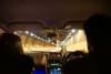 A rear-seat view of the front occupants and an illuminated tunnel roadway.