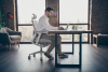 A man in his thirties wearing headphones at a spare room desk, seated in a SIDIZ T20 Ergonomic Office Chair 