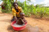 Harriet washes her son in a basin full of water now that she has easy access to clean water at home in, Uganda, May 2024. WaterAid/ James Kiyimba