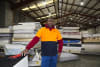 Soft Landing staff member standing in front of end-of-life mattresses, ready to be recycled by hand to recover valuable materials and reduce waste in landfill. 
