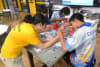 A Makerbus Crew Member assists students from Dripstone Middle School in Darwin to build a dancing robot. Photo: UNSW