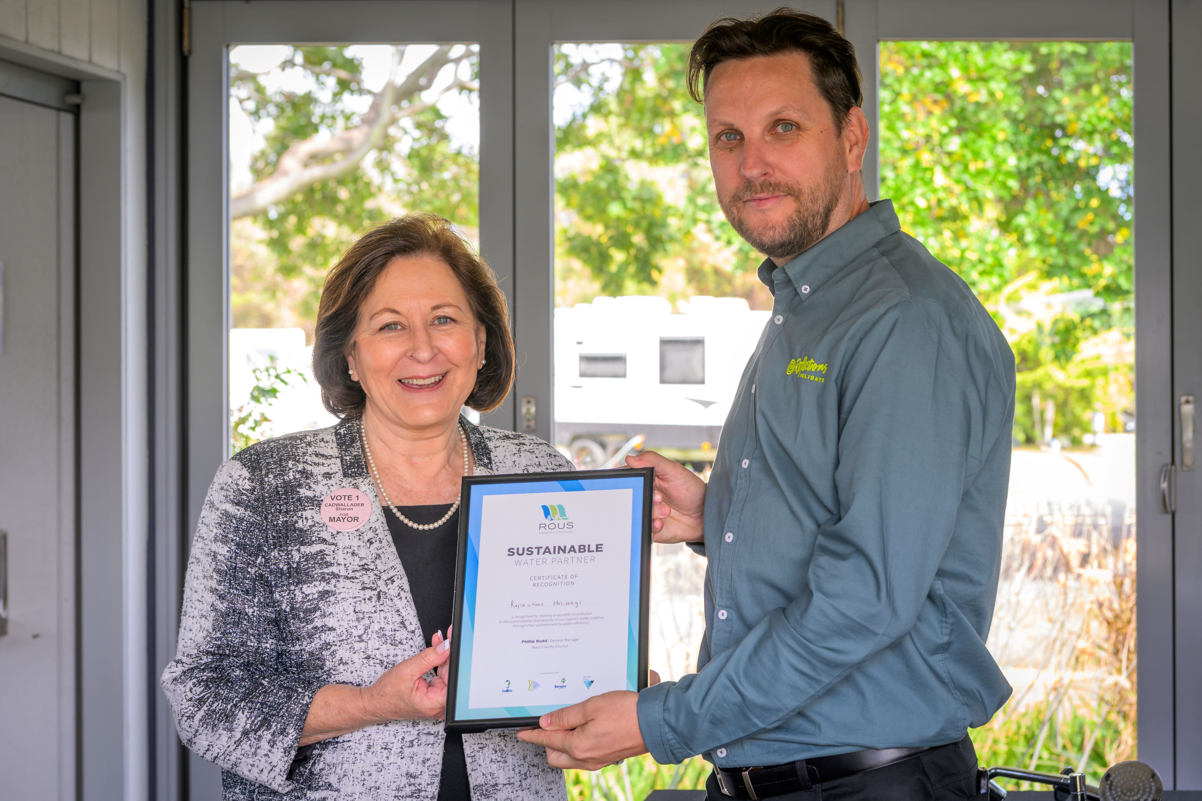 Ballina Mayor Sharon Cadwallader presents Reflections regional park manager Donny Lanesbury with a certificate of recognition for Reflections' efforts as a leader in water sustainability at a ceremony at Reflections Lennox Head today